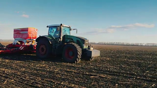斯坦尼康潘拍摄:拖拉机与一个大的播种机正在驾驶穿过田野在太阳视频素材