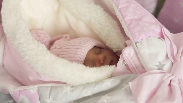 一个新生儿在粉红色的帽子和工作服的特写。视频下载