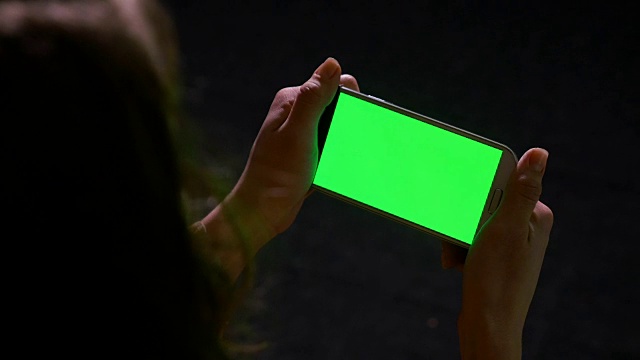 女人用绿色屏幕的智能手机阅读在线内容视频素材