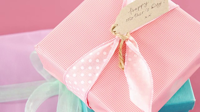礼物盒与快乐的母亲节标签对粉红色的背景视频下载