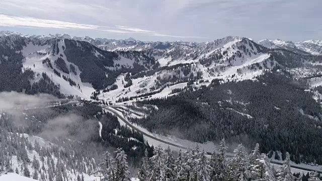 惊人的航拍显示高速公路到冬季滑雪胜地与雪山山峰视频素材