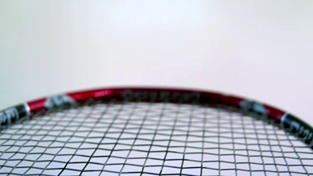 在干净的白色场地上与羽毛球拍相连的羽毛球视频下载