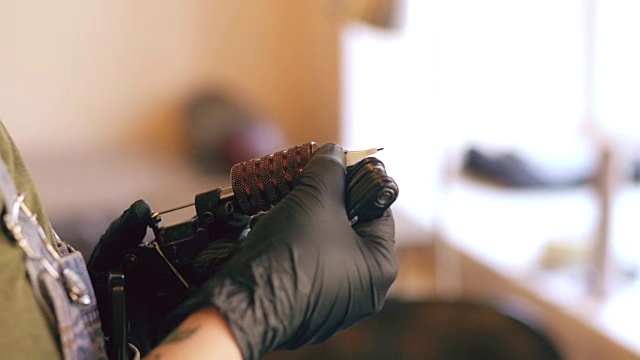 纹身艺术家在室内工作室设置纹身机器的特写视频下载
