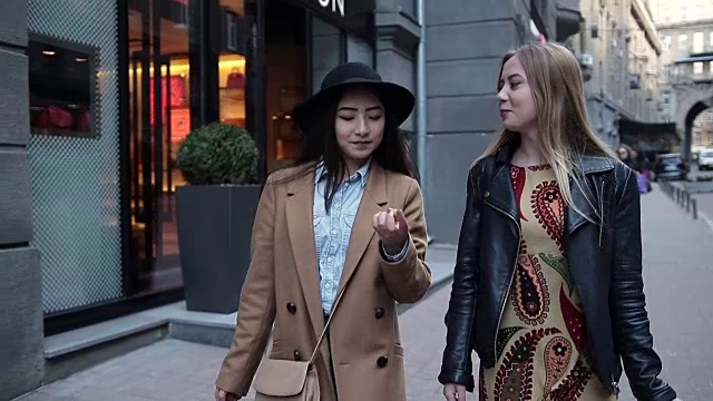 两个年轻女人拿着购物袋走在城市里视频素材