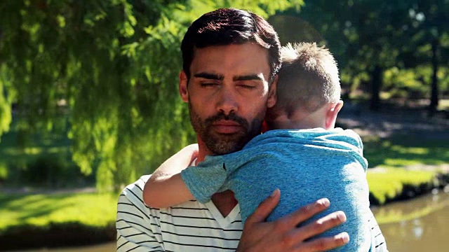父亲抱着熟睡的儿子在公园里视频素材