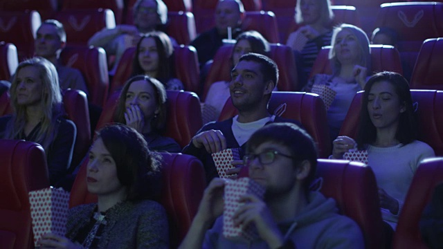 当人们在电影院看电影的时候，男人正在他的座位上。视频素材