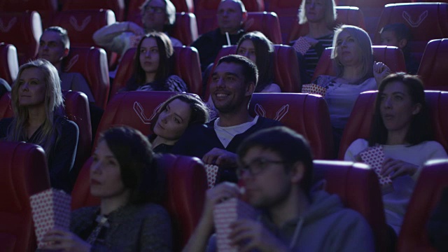 当人们在电影院看电影时，一对夫妇正在他们的座位上。视频素材