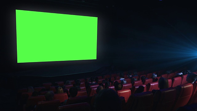 一群人正在看一场绿色屏幕的模拟电影在电影院放映。视频下载