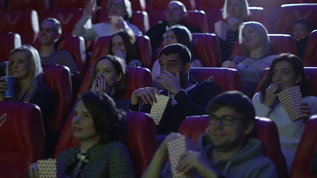 一群人在电影院看恐怖电影时感到害怕。视频素材