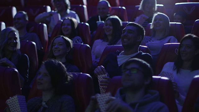 一群人在看一部喜剧电影时笑着在电影院放映。视频素材