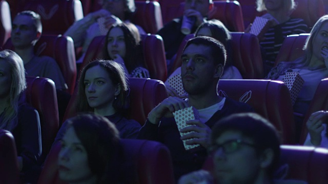 一群人在电影院看恐怖电影时感到害怕。视频素材