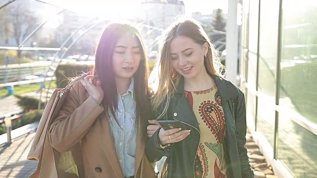 两个年轻女人在街上看智能手机视频素材