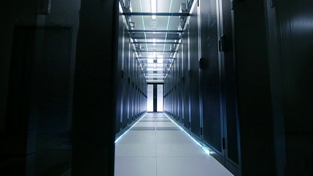服务器工程师走进打开的滑动门，穿过数据中心走廊。工作服务器机架用LED灯闪烁。视频素材