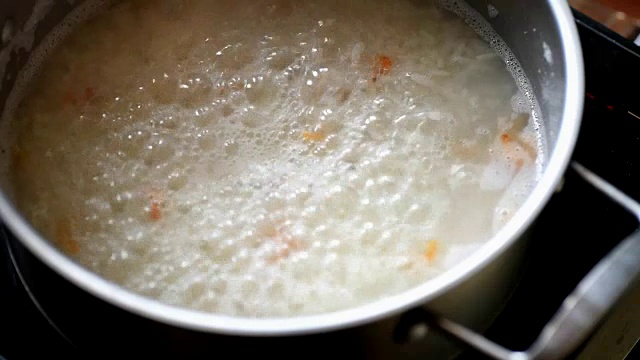 在不锈钢锅中加入开水，用木勺将米饭混合视频素材