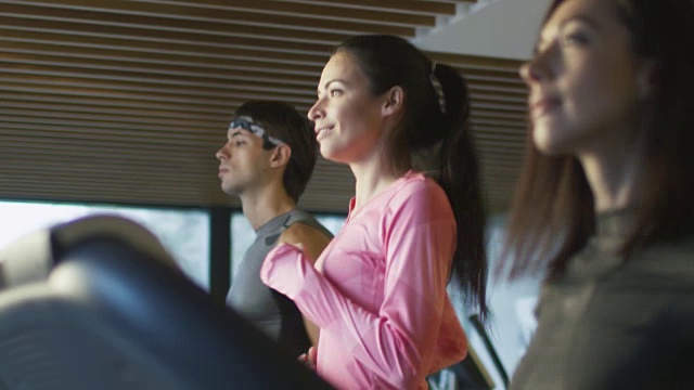 慢动作镜头的年轻运动员男人和女人锻炼和跑步机上在体育馆里。视频素材