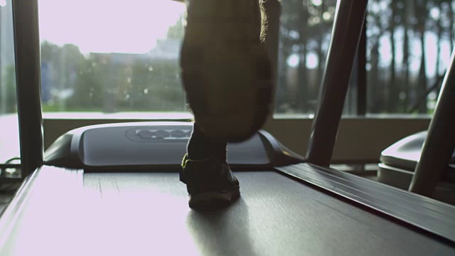 特写镜头的男性剪影对太阳在跑步机上运动健身房。视频素材