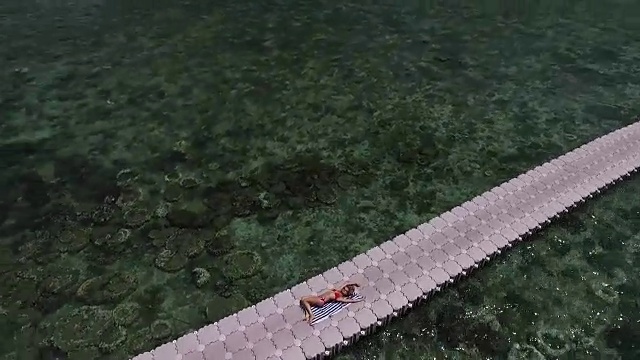 飞过一个躺在浮桥上的穿着红色泳衣的女孩视频素材