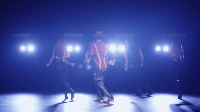 一名戴着帽子、穿着服装的非裔美国男子在灯光下的黑暗舞台上带领一群舞者唱歌。视频素材