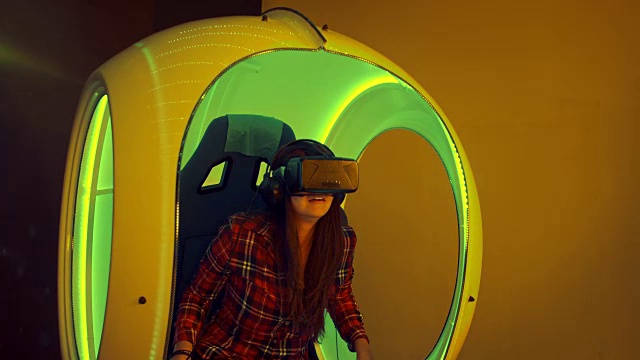 年轻女子坐在交互式移动椅子上体验虚拟现实视频下载