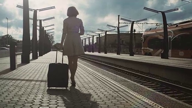 紧接着是自信的女人带着行李走过火车站的照片视频素材