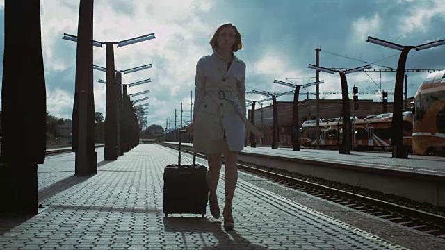 一个女人带着行李走过火车站视频素材