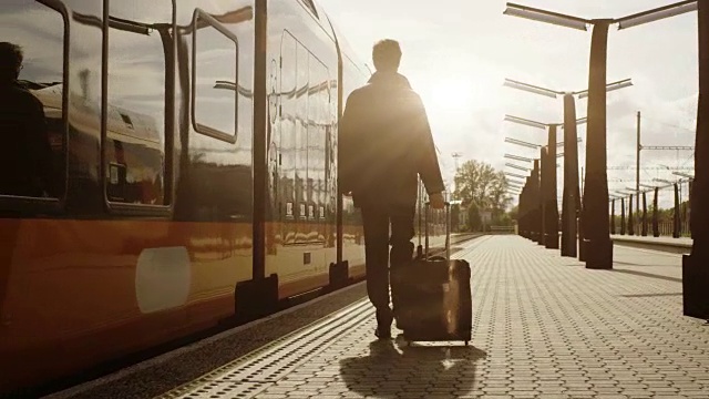 日落时分，自信的男人带着行李走在火车站上视频下载