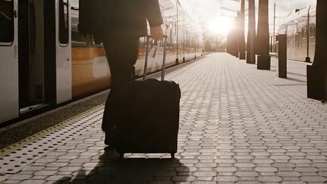 日落时分，自信的男人带着行李走在火车站上视频素材