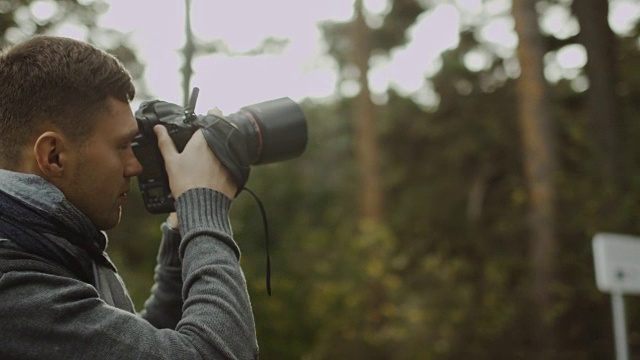 一位男性摄影师正在秋天的森林里拍照。视频下载