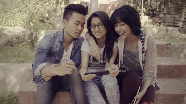 多民族快乐，大学朋友一起分享智能手机。视频素材