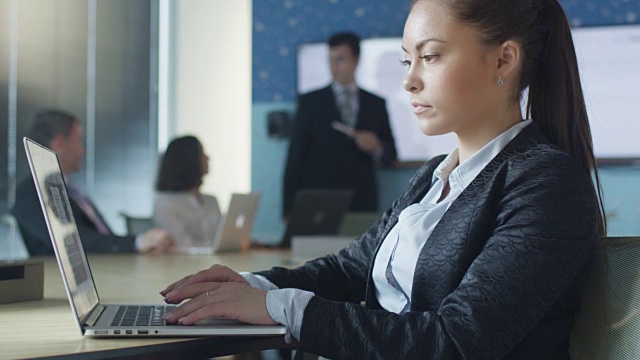 女商人在会议室演讲时使用笔记本电脑。视频素材