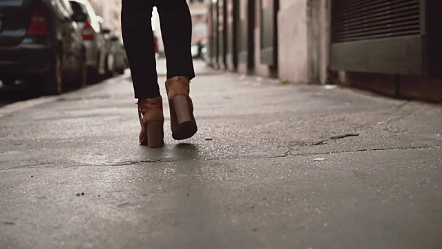 近景时尚的女人走在小街上。女孩穿着高跟鞋穿过城市。慢动作视频素材