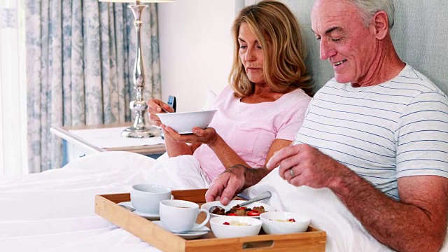 微笑的老年夫妇在床上吃早餐视频素材