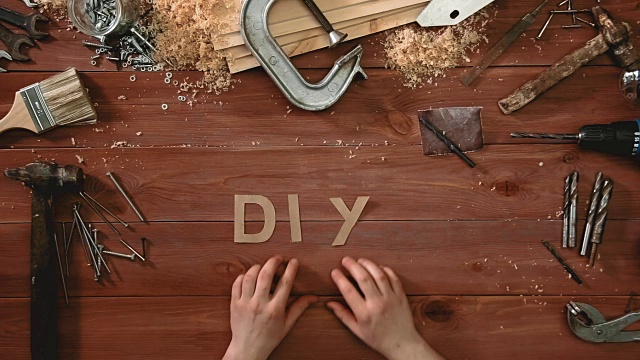 俯视图延时拍摄的手放在木桌上的单词“DIY”视频下载
