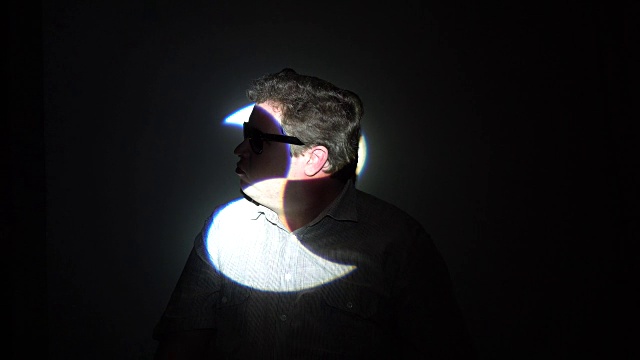 一个被彩色光束照射的胖男人的肖像。视频下载