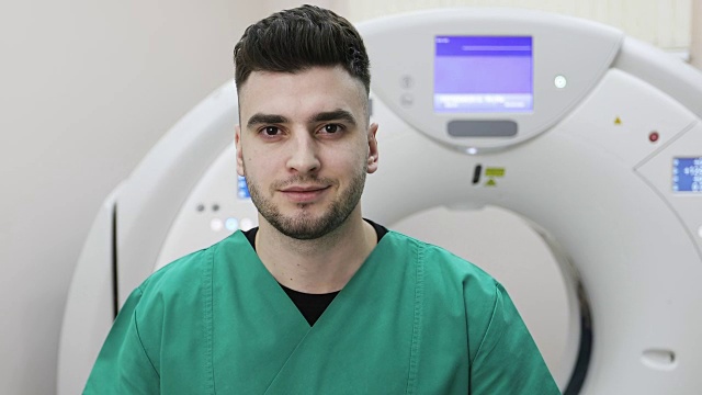 一个年轻的医生在一个新的磁共振成像背景上看着摄像机。视频素材