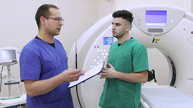 两名年轻医生在新的磁共振成像背景下讨论患者的病史。视频素材
