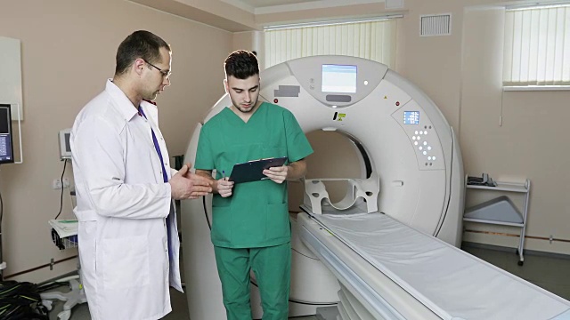 医生讨论治疗诊断门诊。护士按下CT MRI扫描仪设置按钮。视频素材