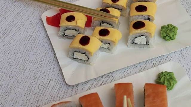 新鲜美味的寿司，三文鱼，生姜，奶酪，芥末和木棒在一个咖啡馆的白色盘子视频素材