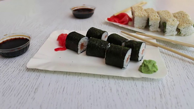 美味的寿司配鲑鱼，寿司配鱼，粉姜，绿芥末，酱油在漂亮时尚的白色背景上视频素材