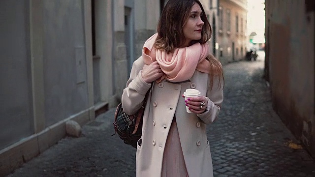 年轻时尚的女人在市中心散步的肖像。快乐的女孩在古老的街道上漫步，喝着咖啡视频素材