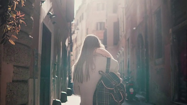 在欧洲的早晨，年轻女子在城市街道上行走的背影。独自探索古城的女孩，四处张望视频素材