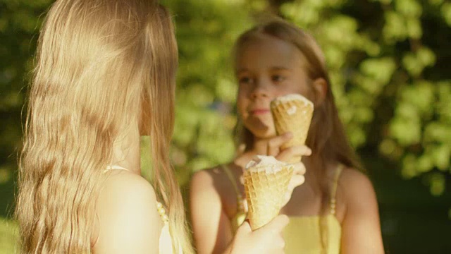 双胞胎女孩在公园吃冰淇淋视频素材
