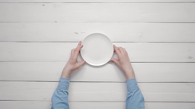 俯视图男性的手把白色的盘子和银器放在白色的桌子上从上面的拷贝空间视频素材