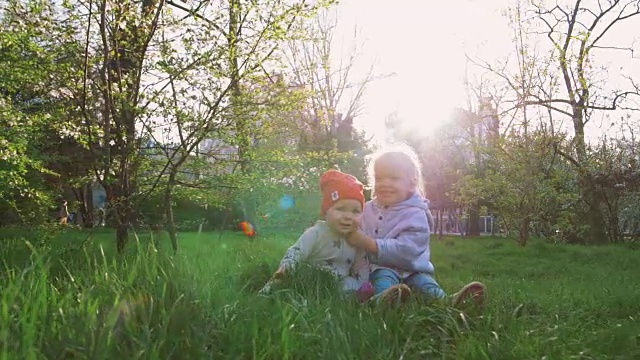 在一个阳光明媚的春天，两个可爱的小妹妹在草地上玩耍视频素材