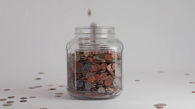 硬币在慢动作中落入透明的罐子视频下载