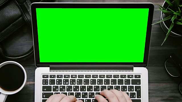 俯视图男性双手工作的笔记本电脑与绿色屏幕在白色的桌子上从上方视频素材