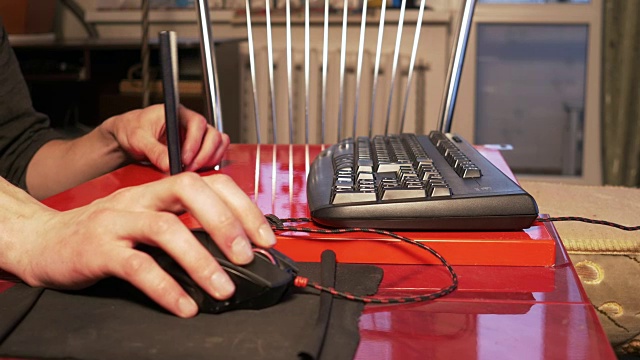 一个年轻人坐在家里的桌子旁用电脑鼠标视频下载