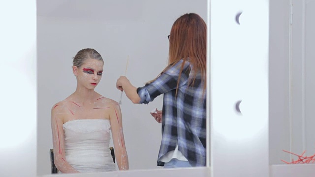 7次。专业化妆师在白色的房间里制作人体艺术视频素材