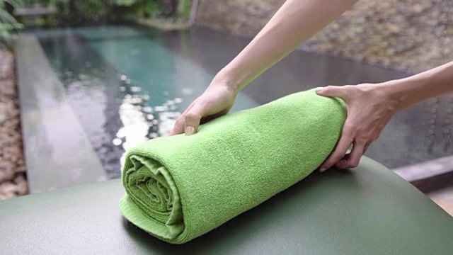 在酒店游泳池附近，女人把干净的毛巾放在躺椅上。视频下载