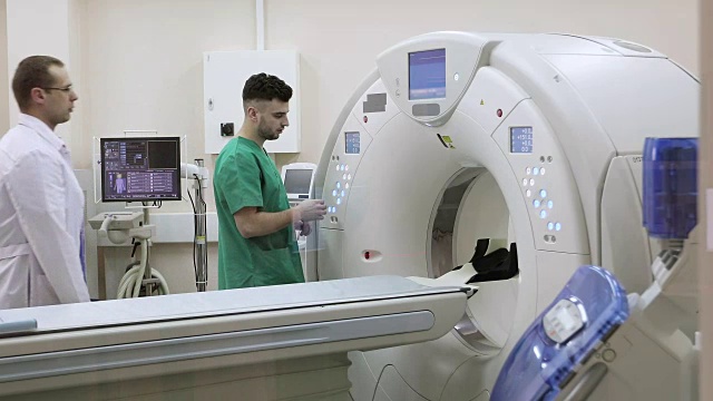4K两位医生按下CT MRI扫描仪设置按钮。视频素材